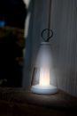 Moderne LED-Laterne mit weißem Licht auf Holztisch, Outdoor-Beleuchtung für Garten oder Terrasse bei Dämmerung.