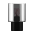 Moderne Tischlampe mit schwarzem Sockel und zylindrischem, transparentem Glas-Lampenschirm, Glühbirne sichtbar.