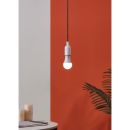 Moderne LED-Hängelampe leuchtet vor orange-weißer Wand, daneben grüne Pflanze und Kerzen auf Tisch.