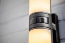 Moderne Außenwandleuchte mit integriertem Bewegungsmelder, warmweißes Licht, schwarze Metallfassung.