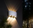 Moderne LED-Außenwandleuchte an grauer Wand, strahlt warmweißes Licht nach oben und unten im Garten.