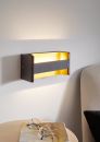 Moderne LED-Wandleuchte in Schwarz mit indirektem, warmweißem Licht an weißer Wand neben Sofa und Tisch.