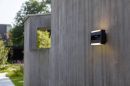 Moderne LED-Außenwandleuchte an grauer Betonwand im Garten bei Tageslicht, stilvolle Außenbeleuchtung.