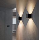 Moderne schwarze Wandleuchten beleuchten eine graue Wand im Flur mit symmetrischem Lichtmuster, Innenbeleuchtung.