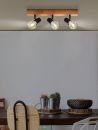 Moderne Deckenleuchte mit drei Spots aus Holz und Metall über Esstisch mit Pflanzen und Stühlen im Esszimmer.